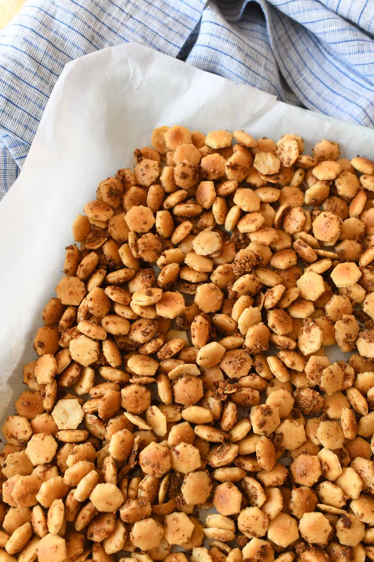 Golden brown oyster crackers on a parchment lined baking sheet.