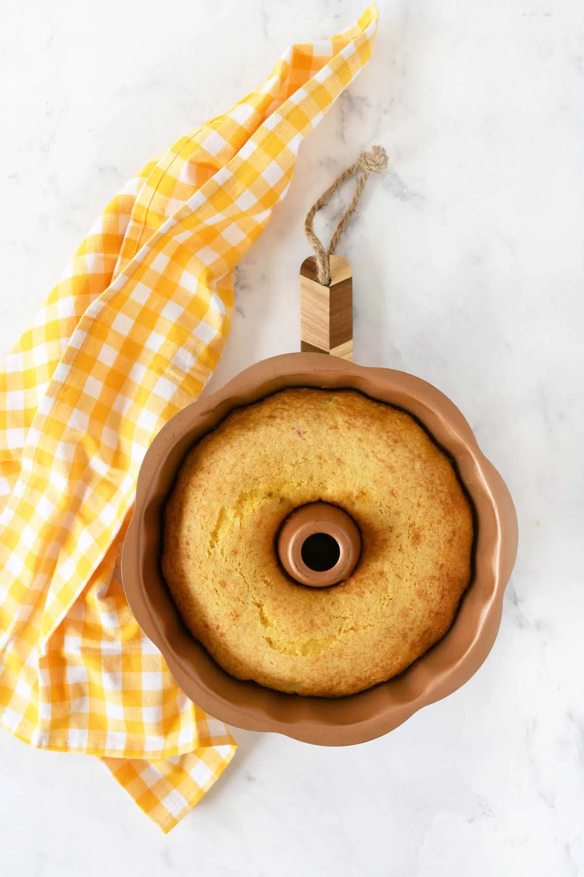 Golden brown fruit bundt cake near a yellow, checkered napkin.