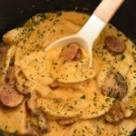 Cheesy pierogi and kielbasa casserole in a black crockpot.