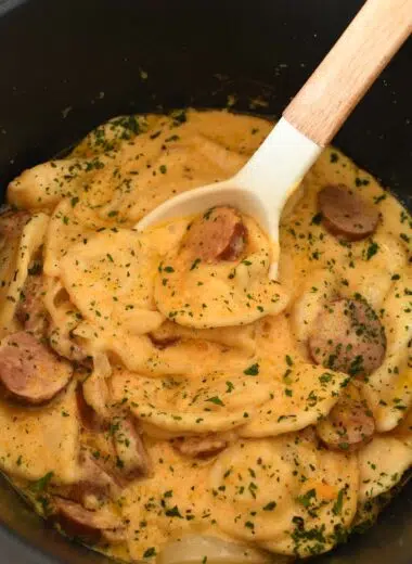 Cheesy pierogi and kielbasa casserole in a black crockpot.