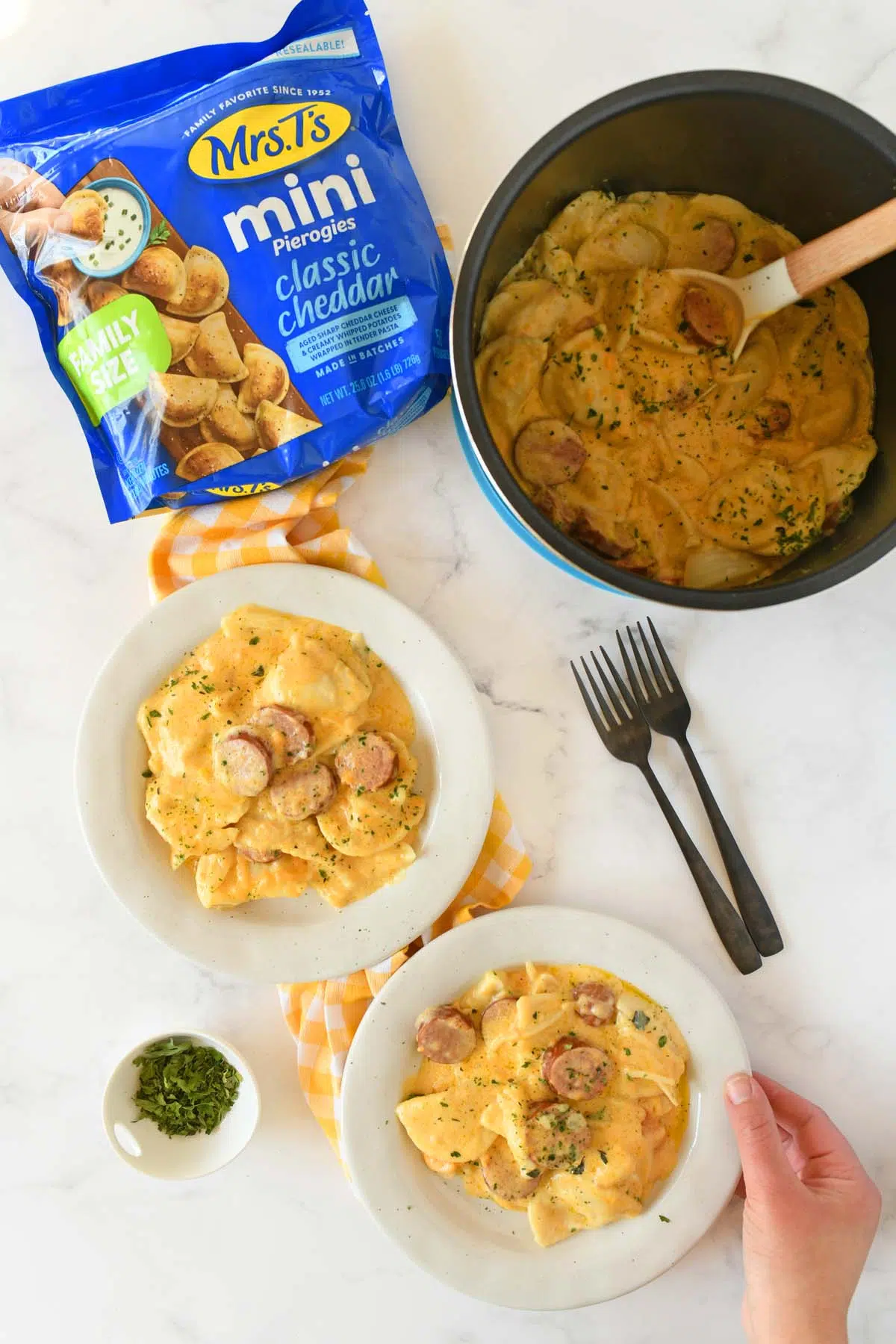 Pierogo casserole on two white plates with a hand grabbing one.