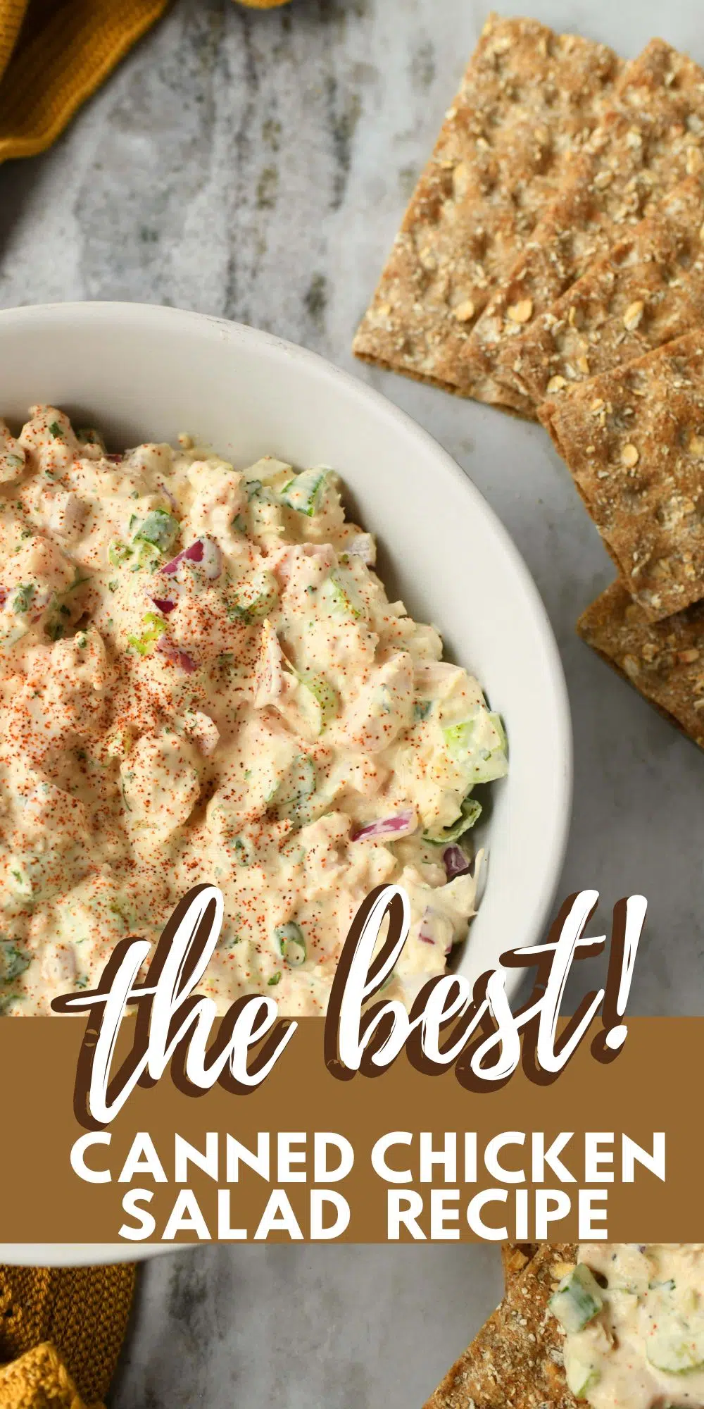 Pinterest image with text that reads: the best canned chicken salad recipe. It shows a bowl of chicken salad near a yellow napkin on a stone surface.