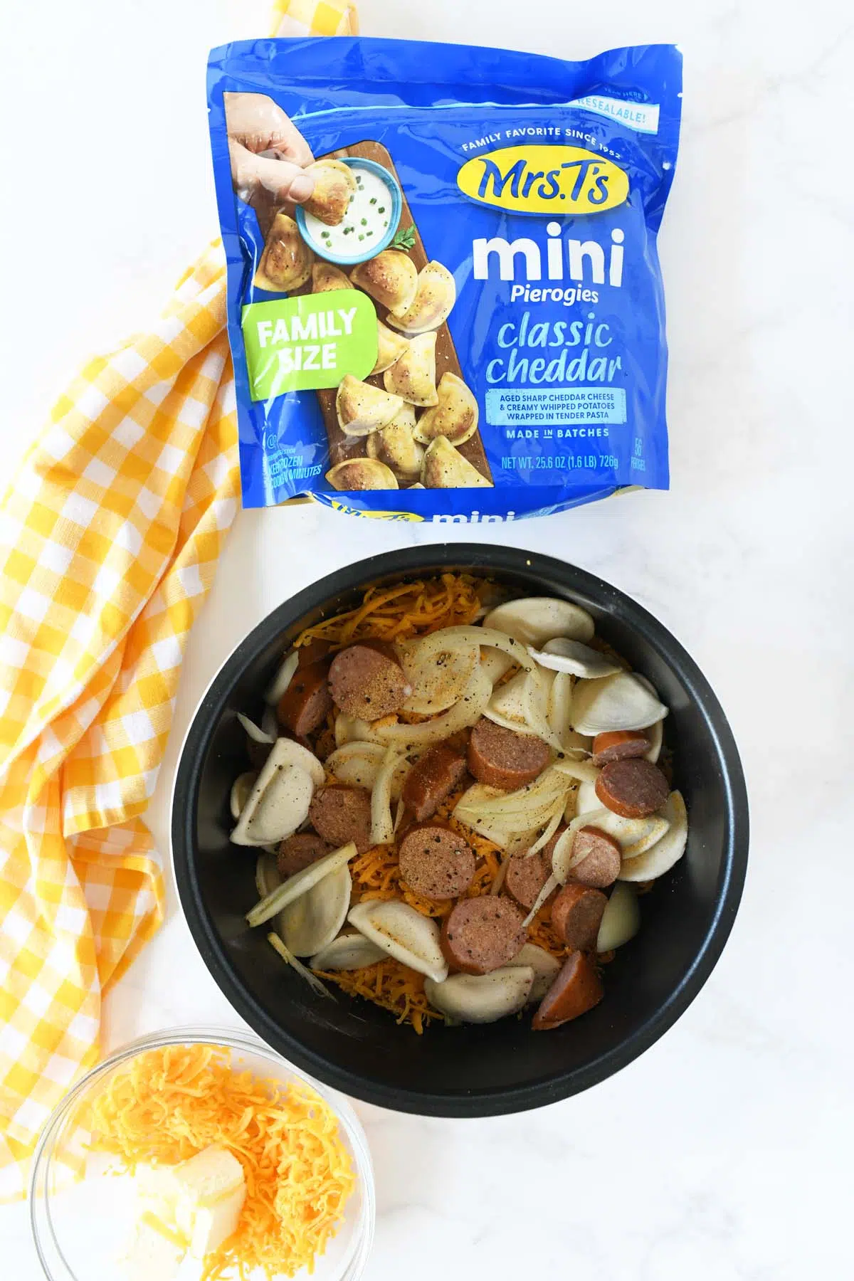 Slow cooker casserole ingredients in a slow cooker insert nearf a blue bag of Mrs T's pierogis.