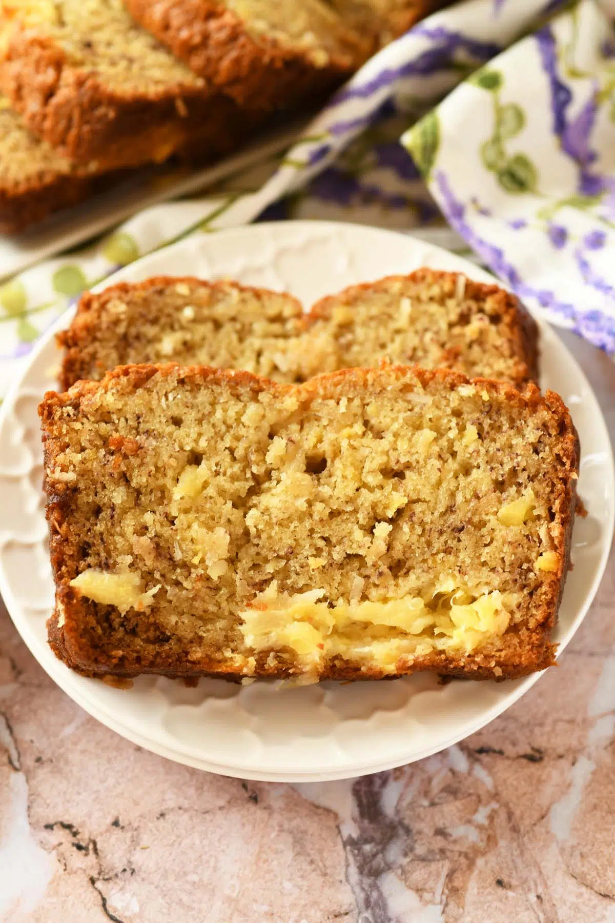 An upclose slice of pineapple banana bread on a small, white plate.