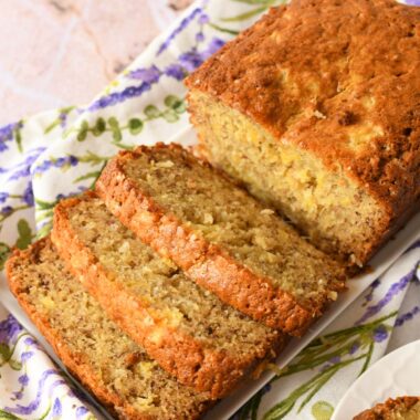 Sliced pineapple banana bread on a white plate wiht a floral napkin.
