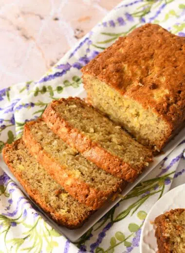 Sliced pineapple banana bread on a white plate wiht a floral napkin.