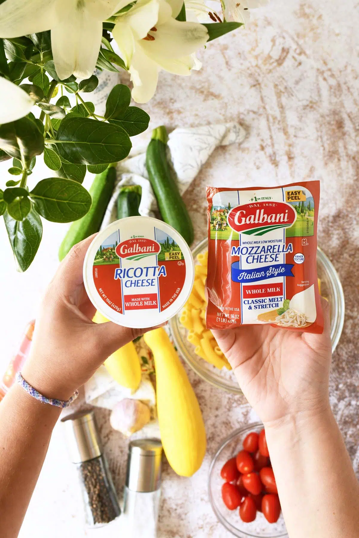 A hand holding up galbani cheeses.