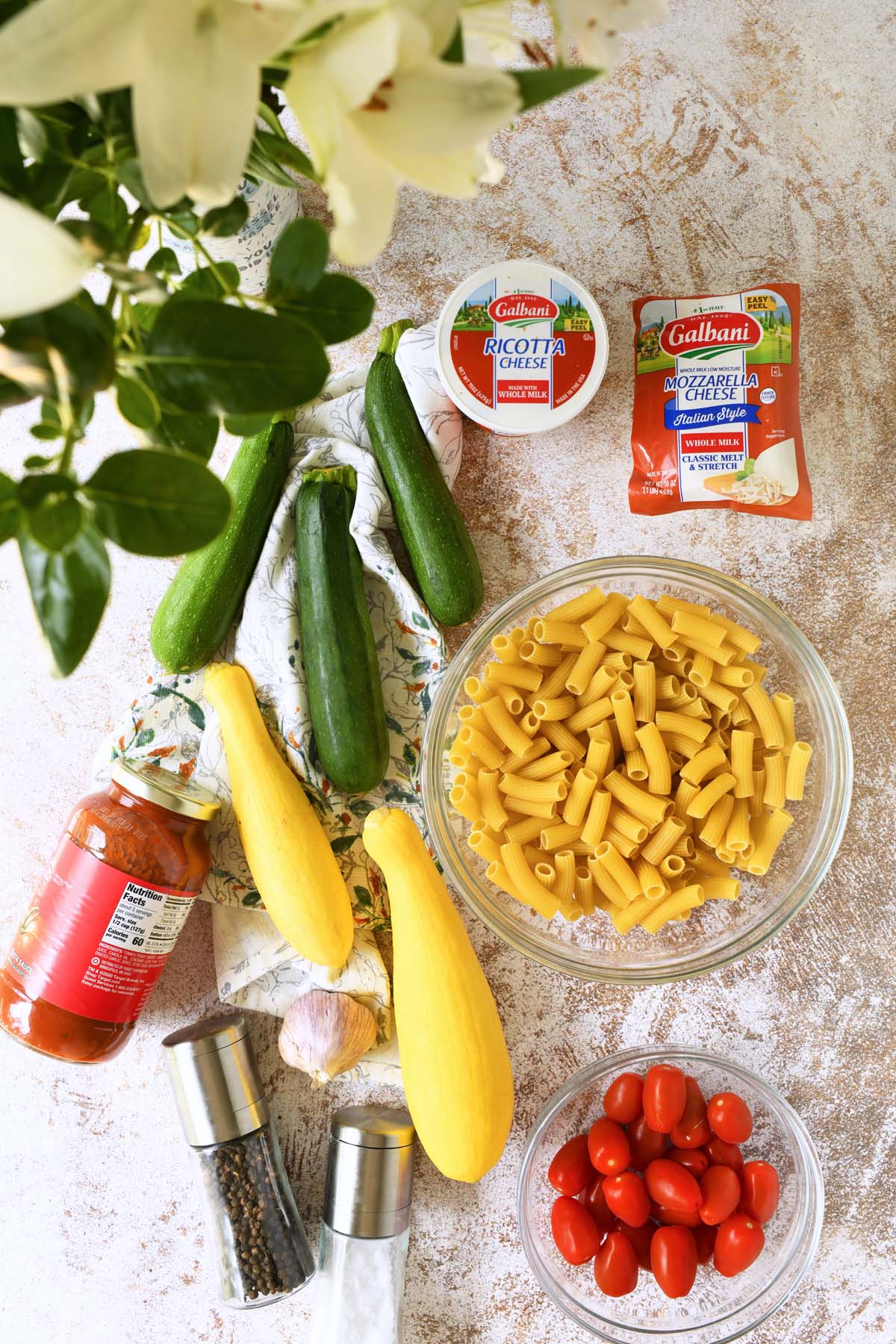 Summer squash baked ziti ingredients on a textured table.