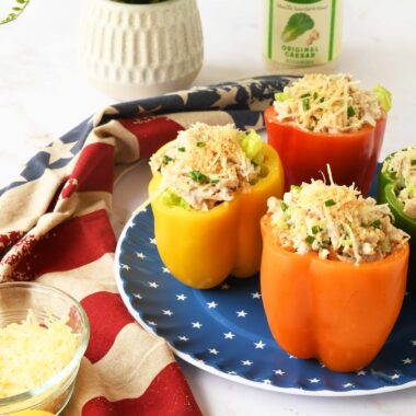 Rainbow peppers with chicken salad inside on a blue star plate. A plant, and patriotic napkin are nearby.