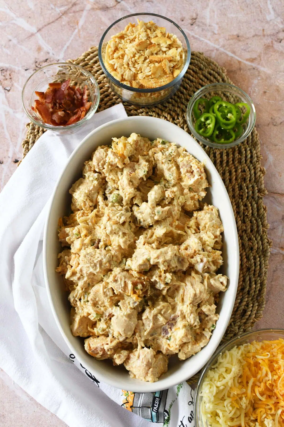 Unbaked jalapeno popper chicken in a white casserole with ingredients nearby.