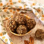 Pecan energy balls in a small yellow dish with a yellow, floral napkin nearby.