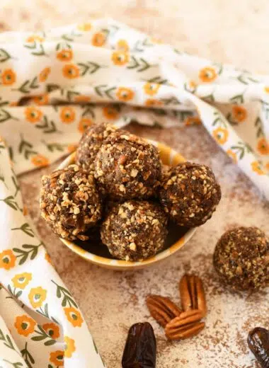 Pecan energy balls in a small yellow dish with a yellow, floral napkin nearby.