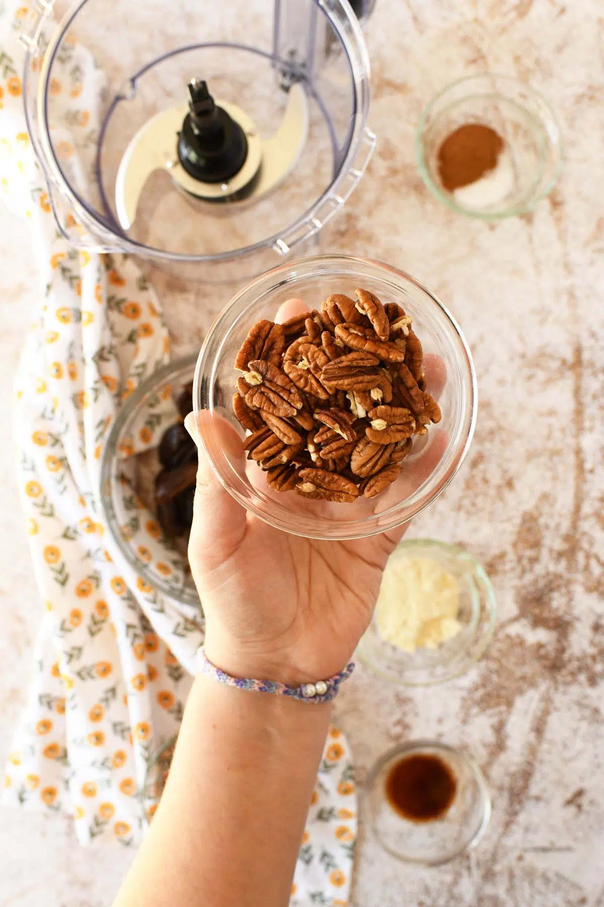 A glass dish of whole pecans in a white hand.