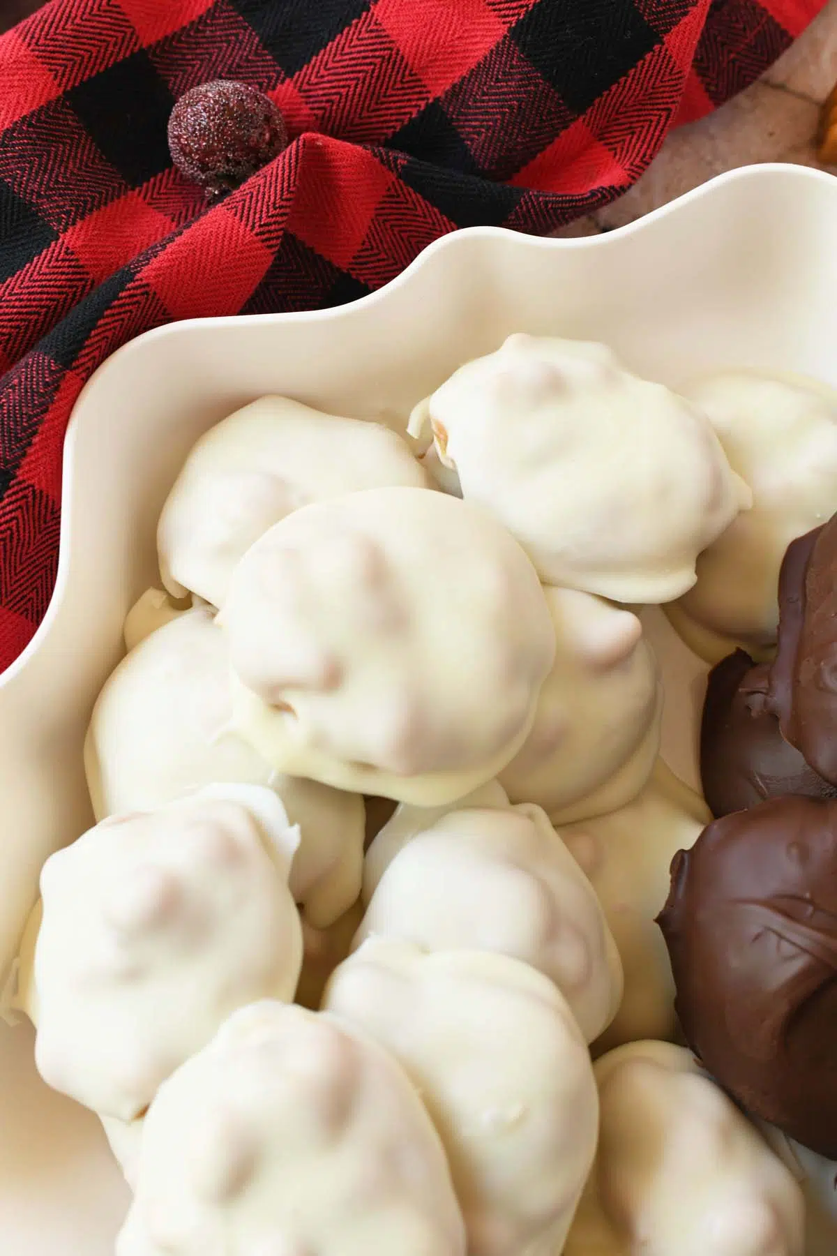 White chocolaet caramel peanut clusters near a red, plaid napkin.