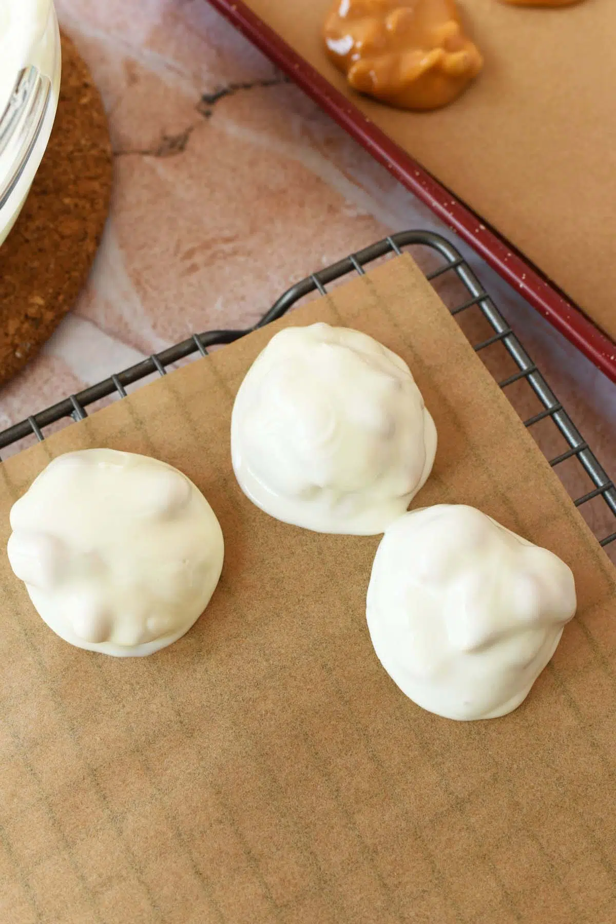 White chocolate coated peanut cluster on a parchment-lined rack.