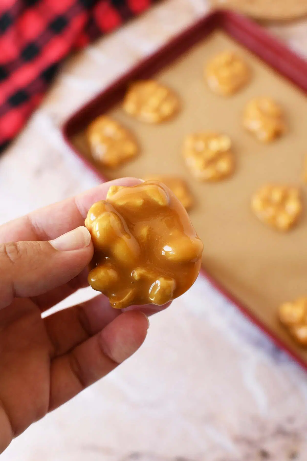 A hand holding a caramel peanut cluster.