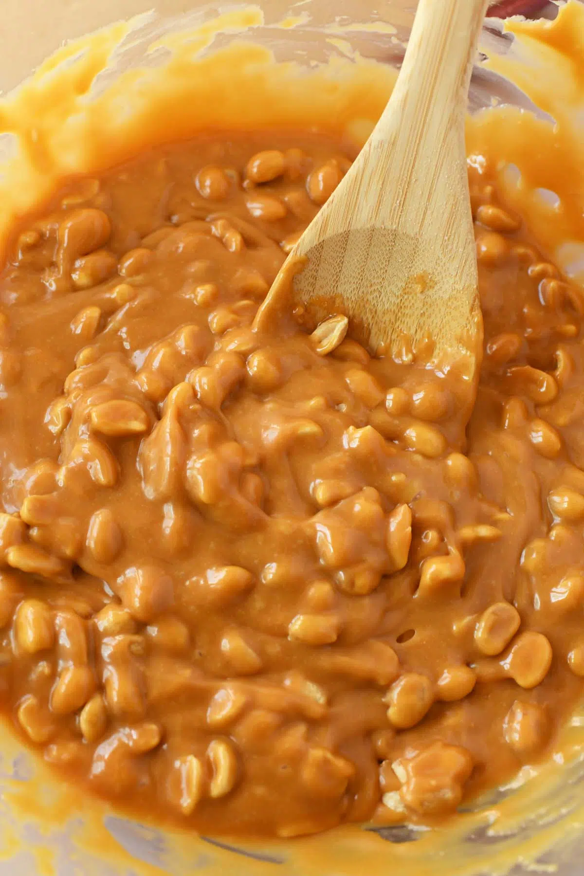A wooden spoon in a caramel, peanut mixture.