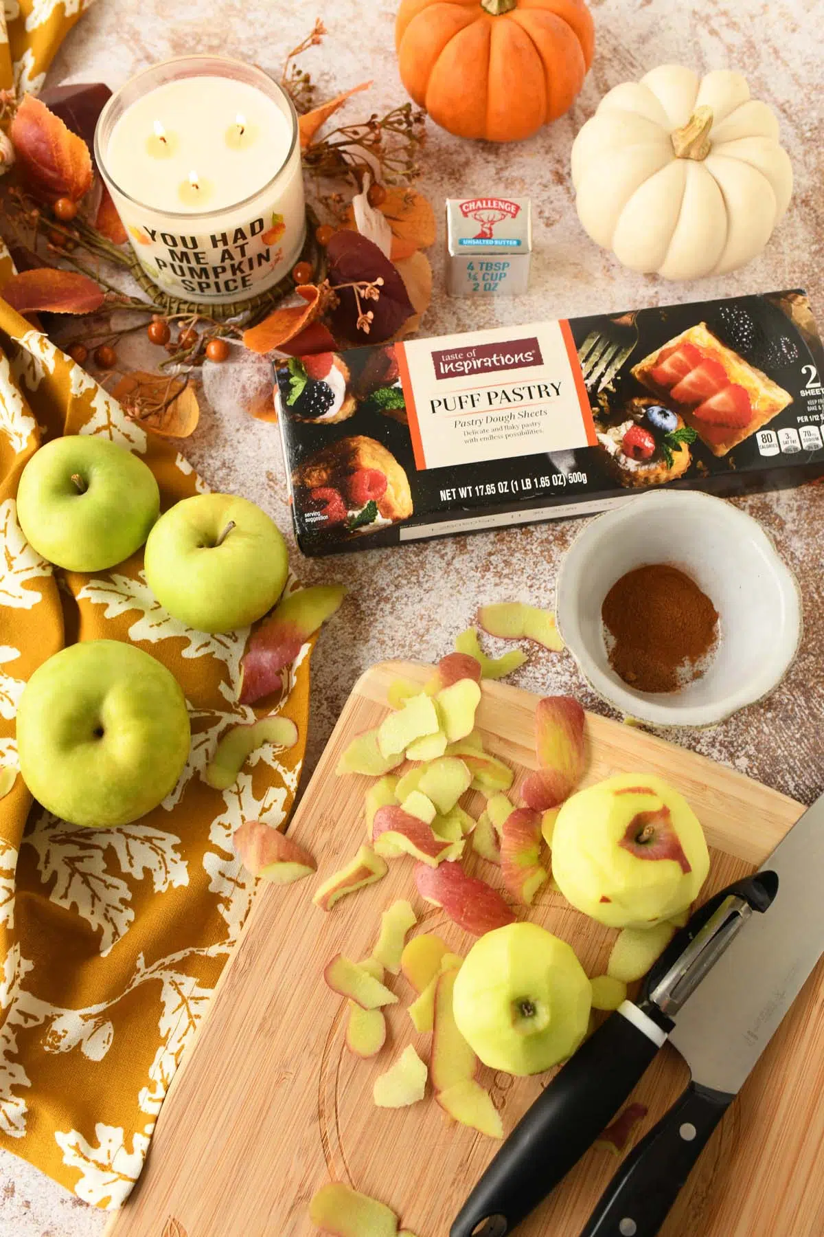 Peeled and unpeeled apples on a cozy, fall-themed table.