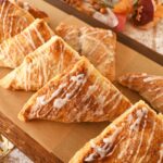 Apple turnovers on a wooden parchment-lined serving platter.