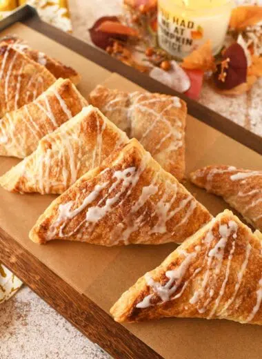 Apple turnovers on a wooden parchment-lined serving platter.