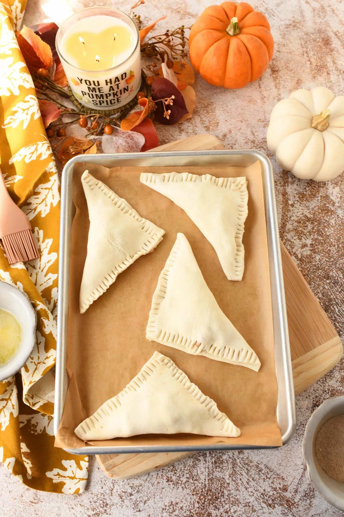 Unbaked puff pastry turnovers on a parchment-lined baking sheet.