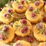 Mini eggnog cheesecakes topped with festive sugared cranberries and rosemary.