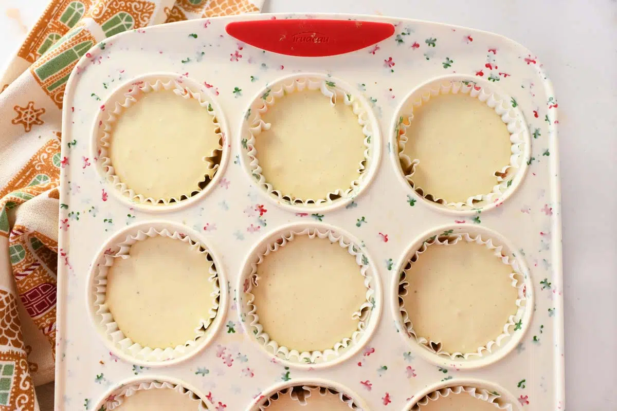 Eggnog cheesecake batter in silicone muffin tin wells.
