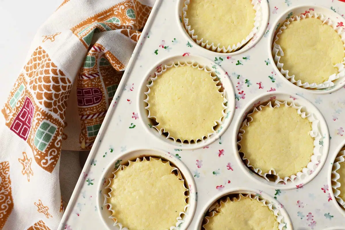 Baked mini eggnog cheesecakes ina holiday themed muffin tin.