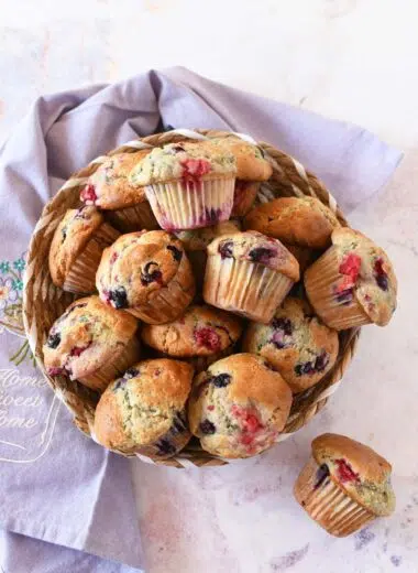 Berry muffins in a basket near a purple napkin.