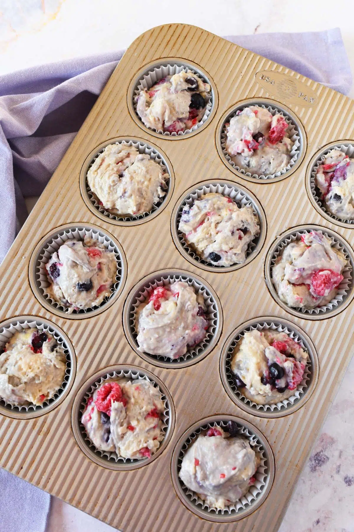 Berry sourdough batter in muffin tin liners.