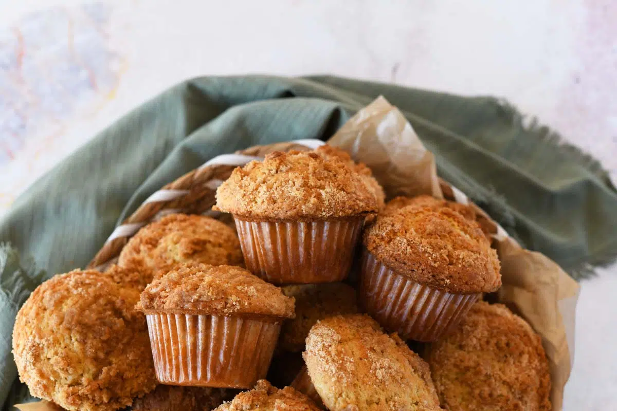 Coffee cake sourdough muffins in a basket with a green napkin.