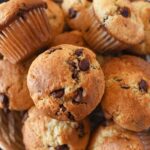 Sourdough chocolate chip muffins in a basket near a blue napkin.