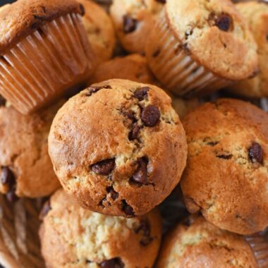 Sourdough chocolate chip muffins in a basket near a blue napkin.