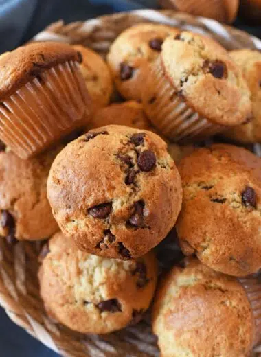 Sourdough chocolate chip muffins in a basket near a blue napkin.