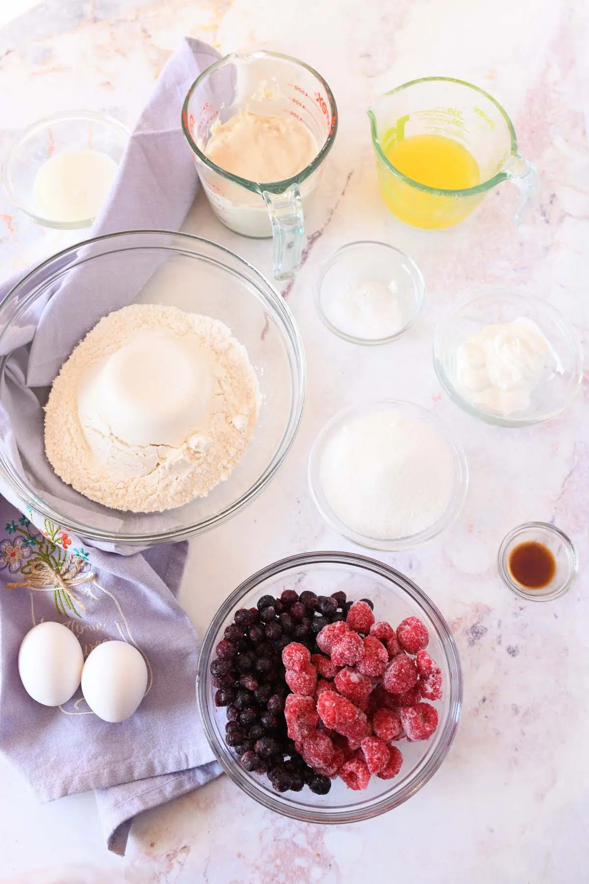 berry sourdough muffins in small dishes on a marble surface with a purple napkin.