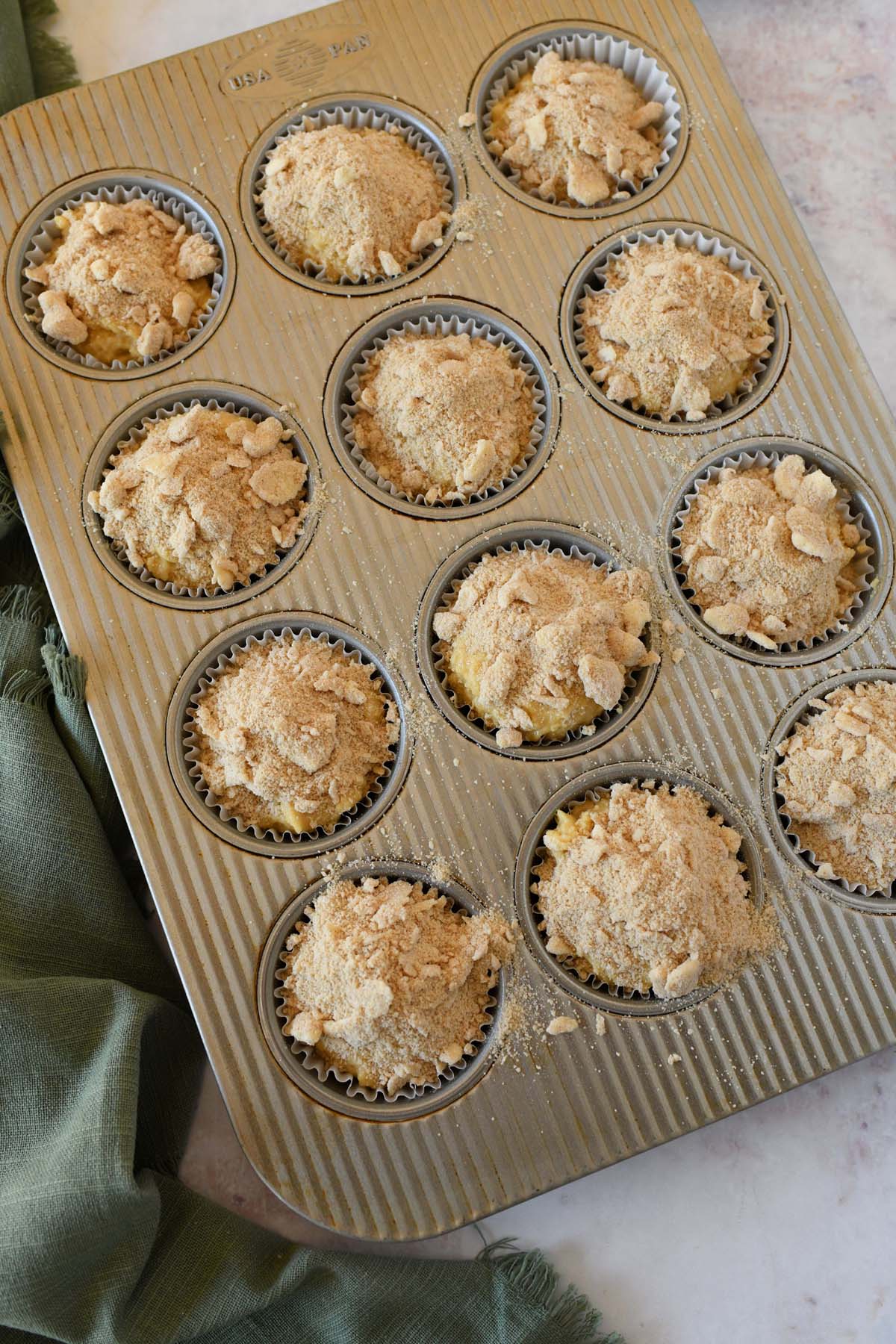 Raw coffee cake muffin batter in a muffin tin.