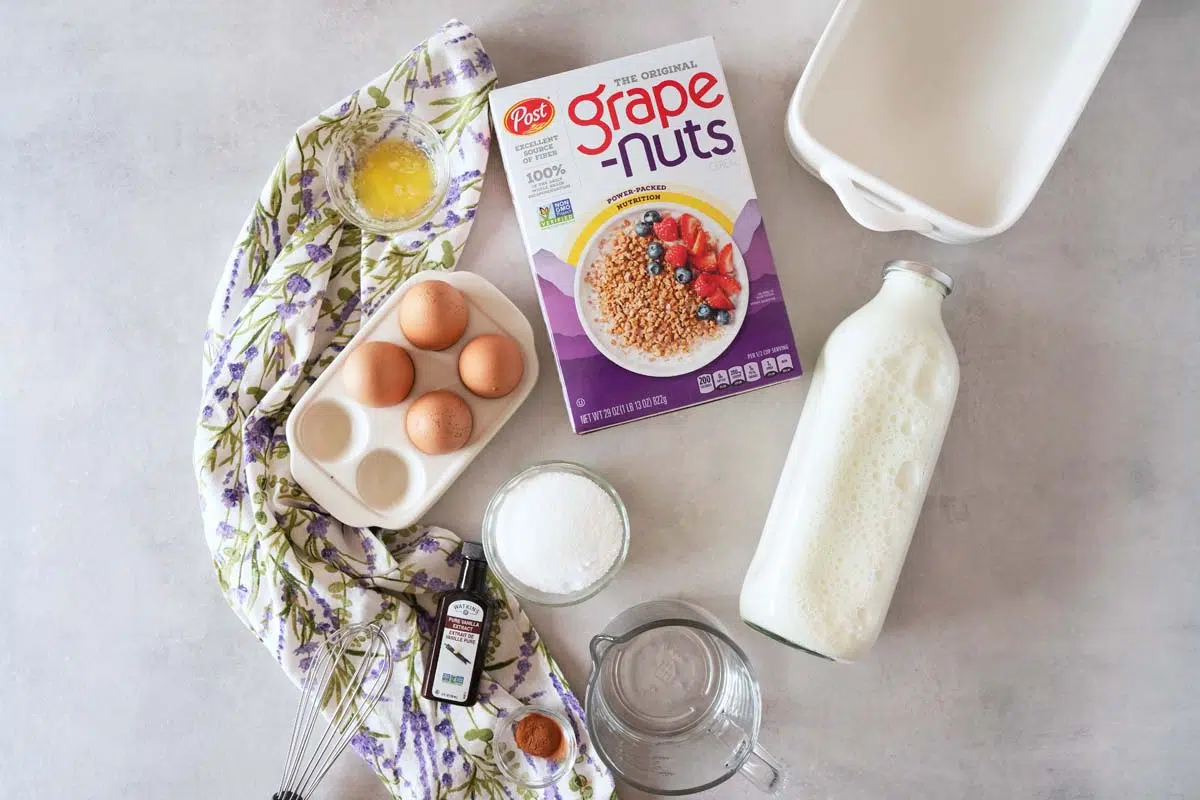 Grape-Nuts Pudding ingredients on a grey, stone table with a purple, flowered napkin.