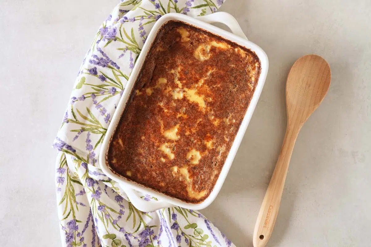 A 7x11 white, rectangle dish of baked Grape-Nuts pudding with a purple, floral napkin.