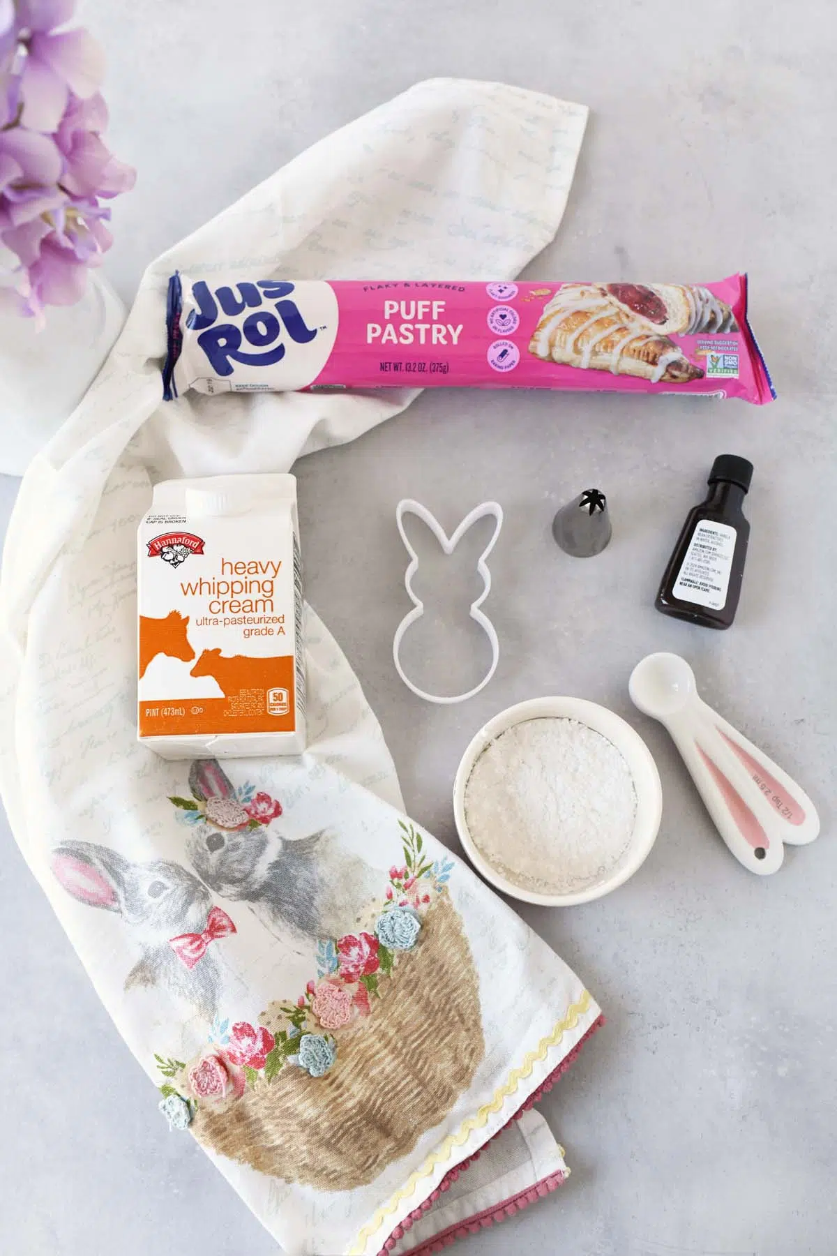 Bunny cream puff ingredients and supplies on a stone table with an Easter napkin.