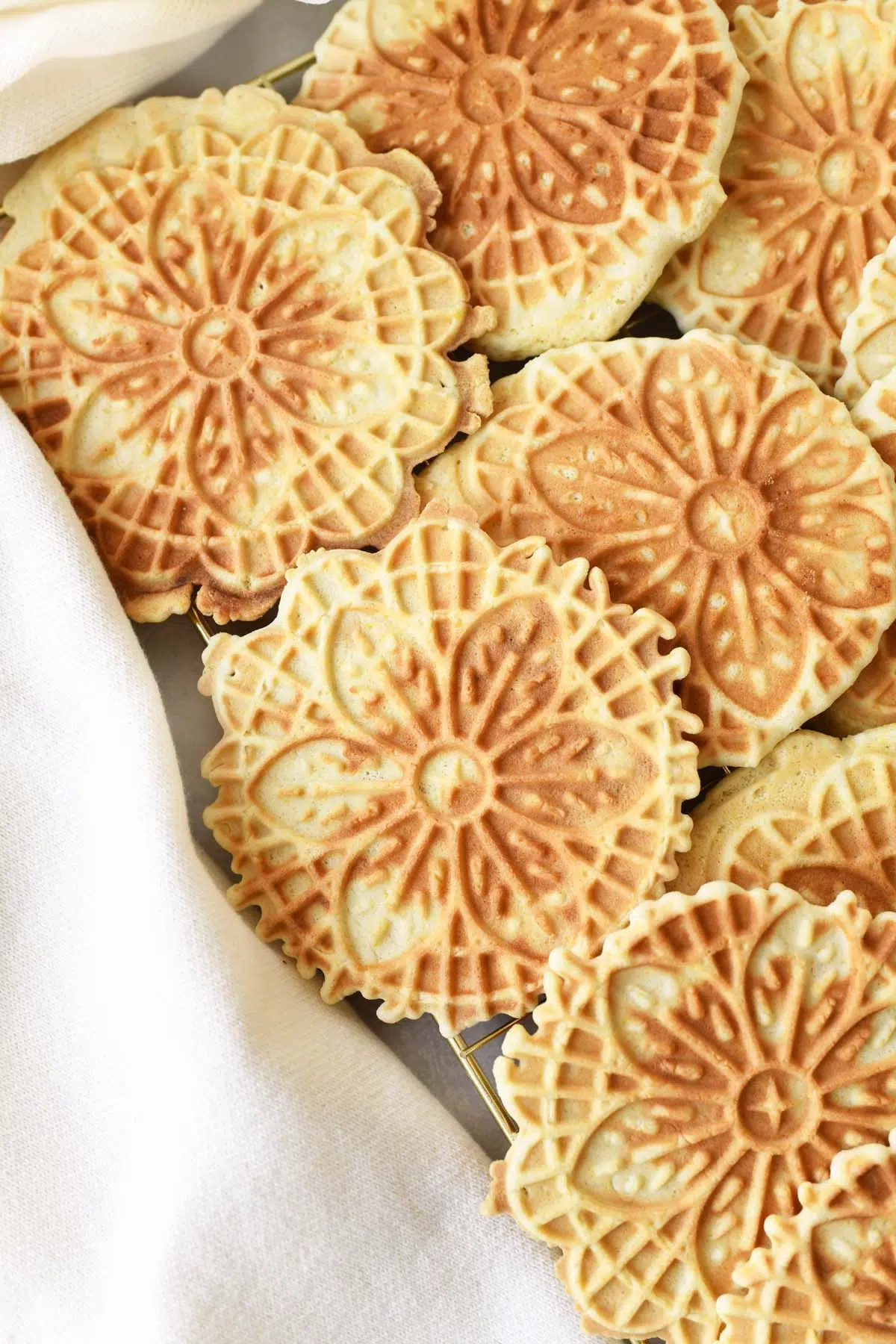 Golden brown pizzelle cookies on a tray near a white napkin.
