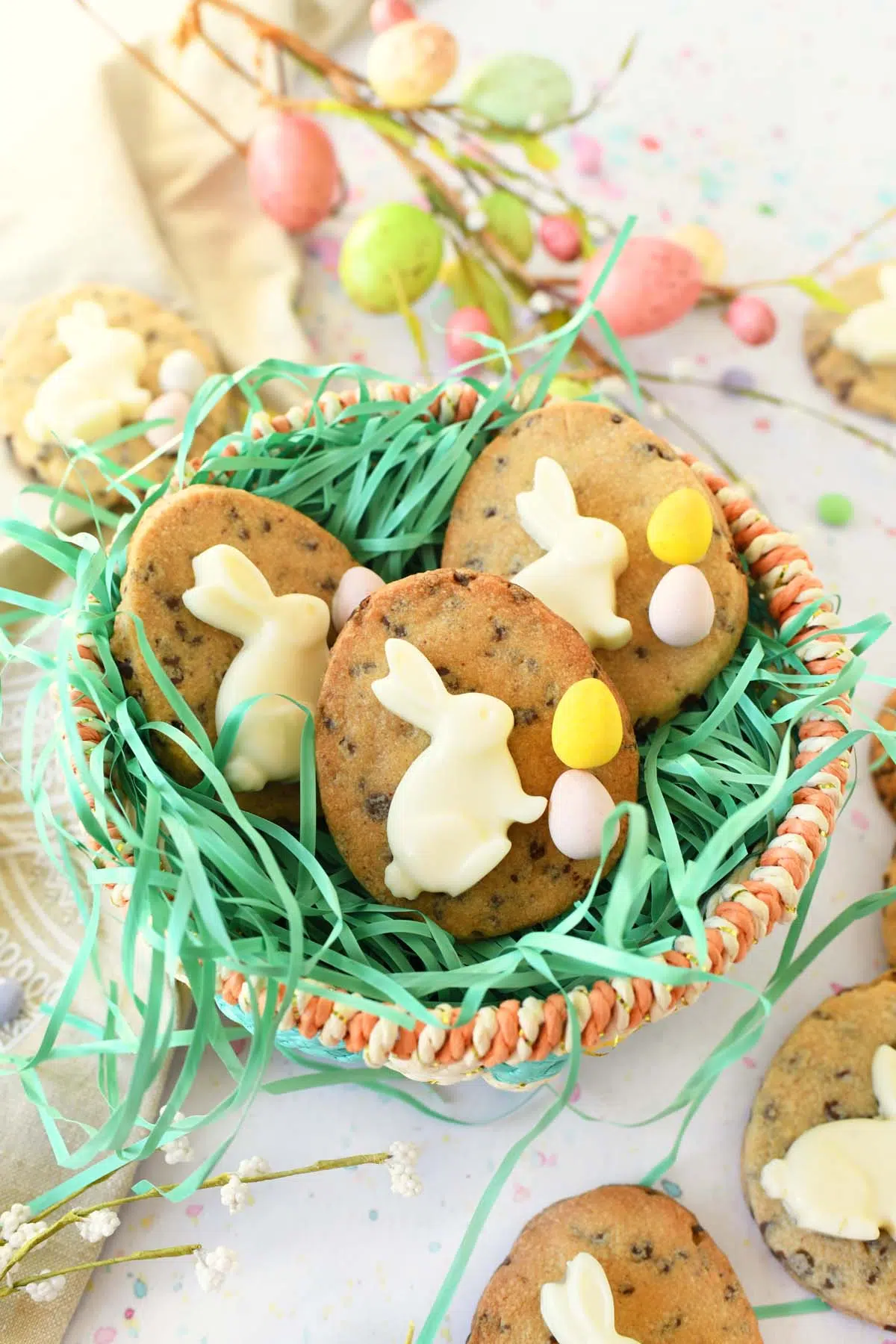 Bunny egg cookies inside a pastel basket with green easter grass inside.
