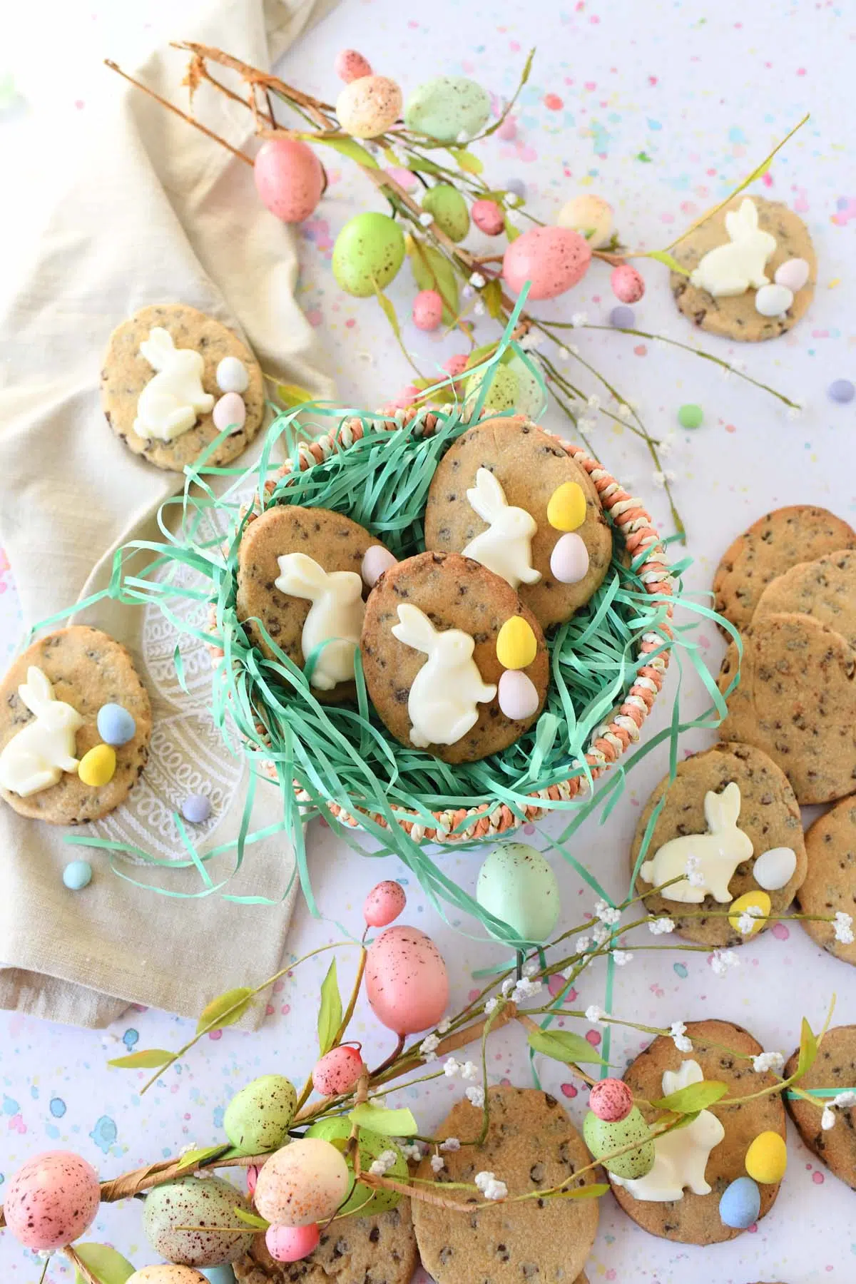 Bunny Easter egg cookies inside on a pastel Easter basket with green grass, and pastel egg greenery nearby.