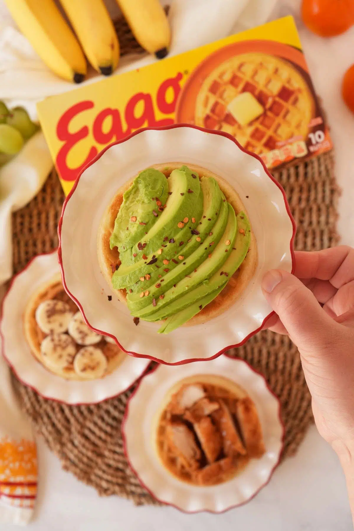 An Eggo waffle topped with sliced avocado and red pepper flakes.