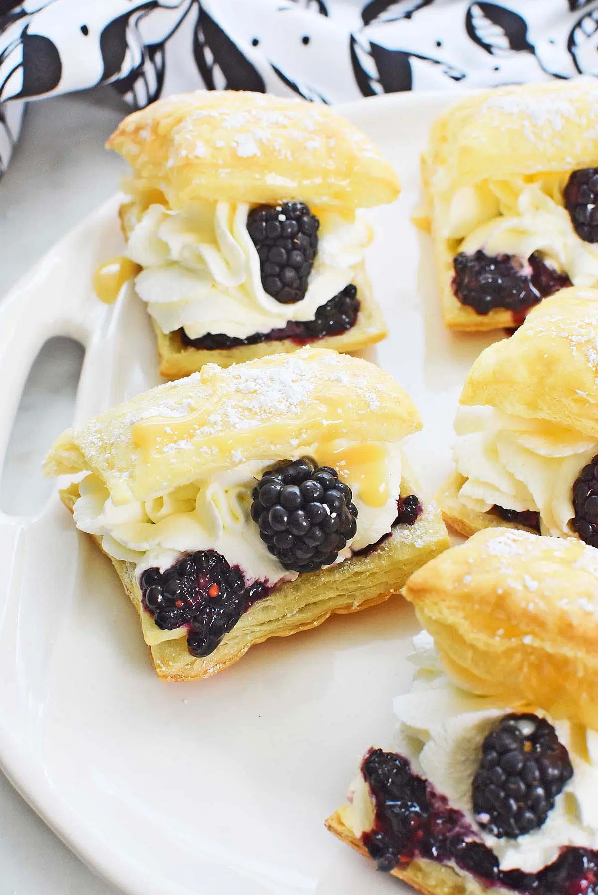 Blackberry puff pastry cream puffs on a white platter.