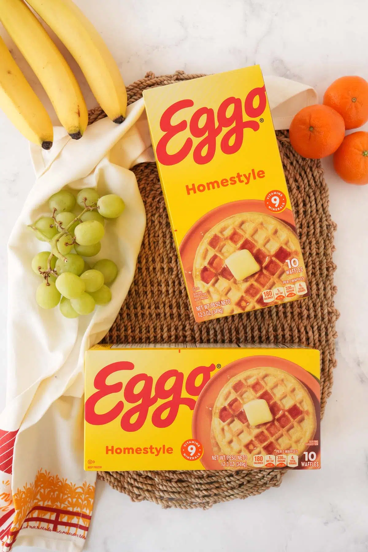 Two yellow boxes of Eggo waffles near fresh fruit.