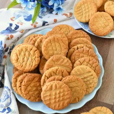 Peanut butter cookies on a blue plate with blue flowers and a napkin nearby.