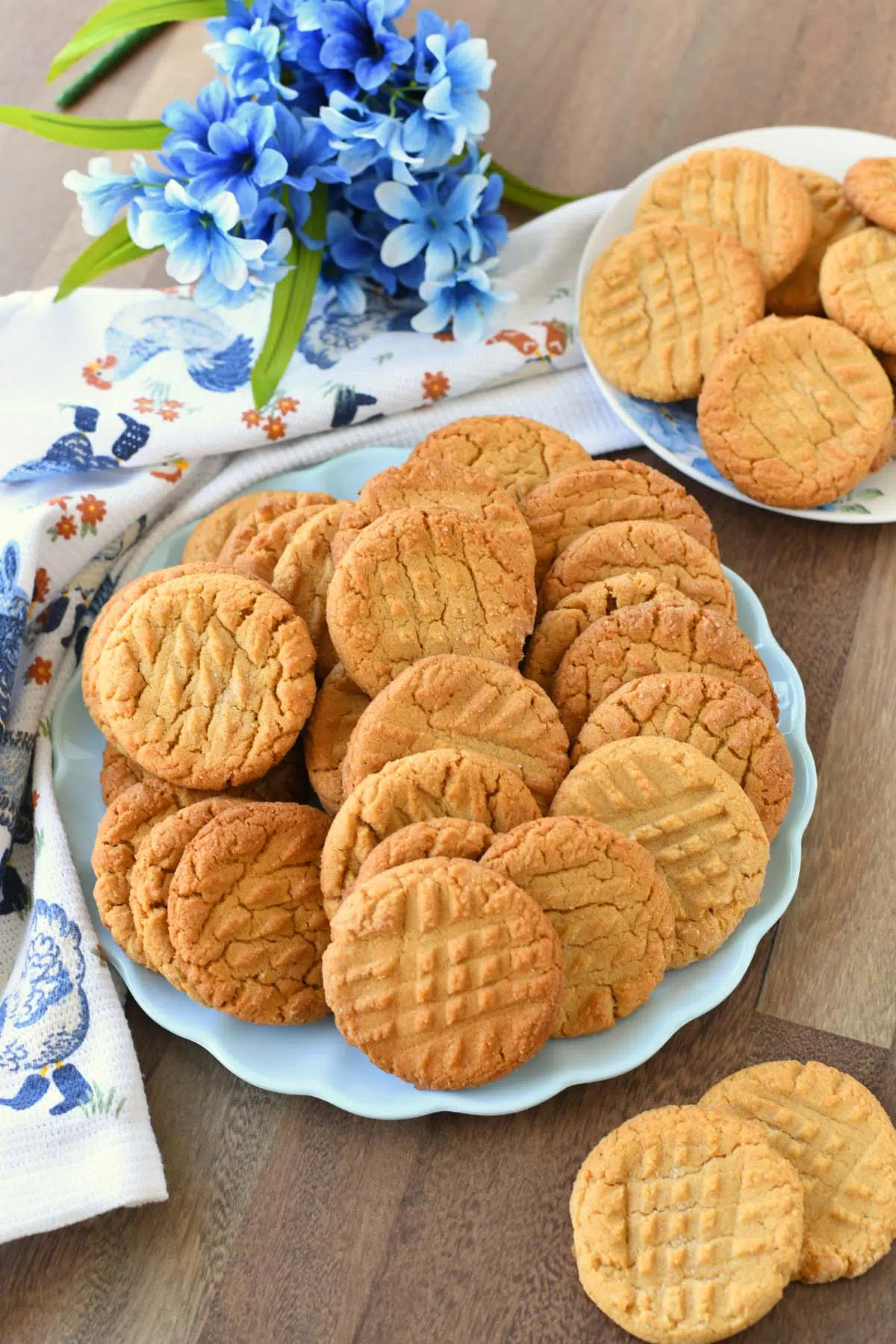 Peanut butter cookies on a blue plate with blue flowers and a napkin nearby.
