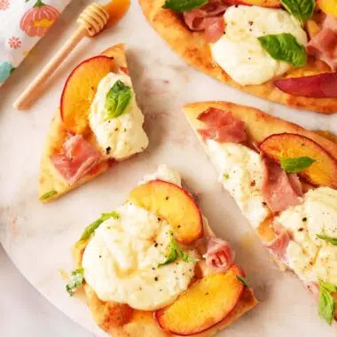 Sliced Peach flatbread with peach slices, ham, basil, and a drizzle of hot honey.