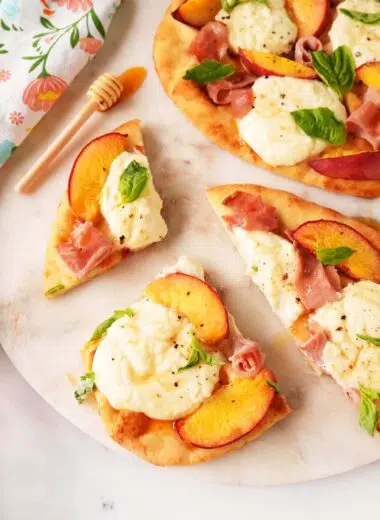 Sliced Peach flatbread with peach slices, ham, basil, and a drizzle of hot honey.
