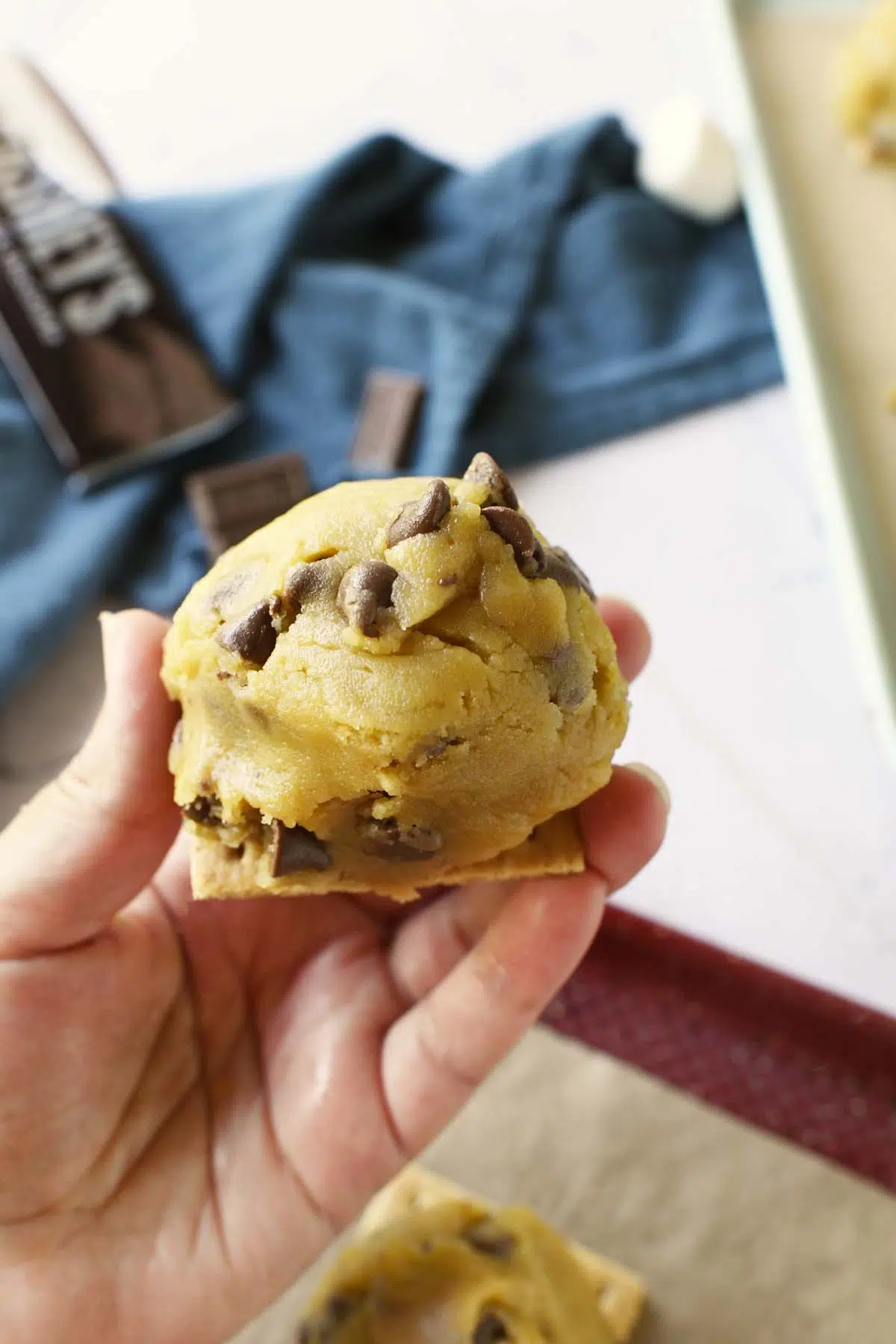 A hand holding up a raw dough ball on a graham cracker.